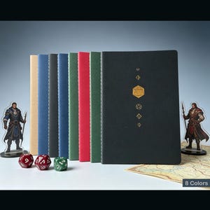 Puede incluir: Una colección de ocho cuadernos en varios colores, incluyendo beige, azul, rojo y verde. El cuaderno negro presenta un diseño geométrico dorado. Dados y figuras de personajes en primer plano. El texto "8 Colors" es visible.