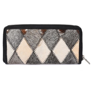 May include: A black leather wallet with a zipper closure. The wallet is made of a patchwork of different colored furs, including gray, white, and brown.