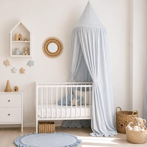May include: A nursery room featuring a white crib with a blue and white striped canopy, a white dresser, a wooden rocking horse, a round blue rug, two woven baskets with plush toys, a house-shaped wall shelf, and a round sunburst wall mirror.