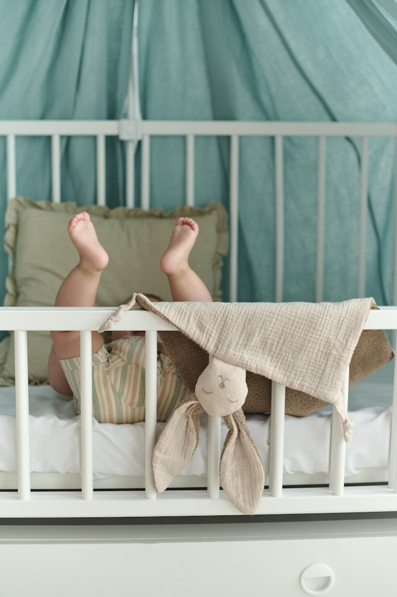 A baby's feet are visible in a crib, with a stuffed bunny toy resting on the bed.
