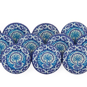 Könnte beinhalten: Ein Satz von zehn blauen und weißen Keramiktellern mit einem Baumdesign. Die Teller sind in einem Halbkreis angeordnet.