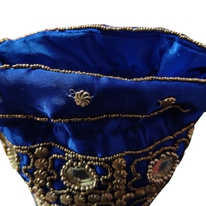 May include: A blue fabric pouch with gold embroidery and mirror accents. The pouch is lined with blue satin.