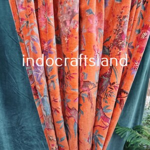 May include: Orange velvet fabric with a floral and bird print. The fabric has a textured surface and a soft, luxurious feel.