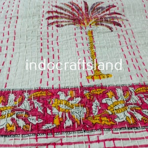 May include: White cotton kantha quilt featuring a pink and yellow palm tree design. The quilt has a pink and white border with a floral pattern. The text "indocraftsland" is visible in the centre of the quilt.