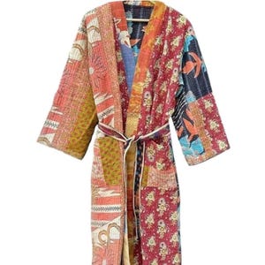 Könnte beinhalten: Eine lange, bunte Patchwork-Robe mit einem Bindegürtel. Die Robe besteht aus verschiedenen Stoffen und Mustern, darunter Blumen, geometrische Muster und Paisley. Die Robe ist ein lebendiger Mix aus Rot, Orange, Gelb, Grün, Blau und Lila.