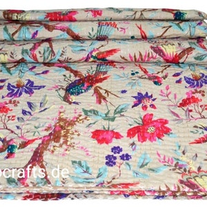Könnte beinhalten: Eine beige Kantha-Steppdecke mit floralem und Vogelmuster. Die Steppdecke ist in den Farben Pink, Rot, Blau und Grün gehalten. Die Steppdecke ist in drei Teile gefaltet und der Text "indocrafts.de" ist in der unteren rechten Ecke sichtbar.