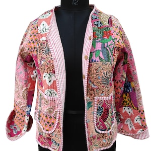 Könnte beinhalten: Eine gesteppte Jacke in Rosa und Weiß mit Blumenmuster und Knopfleiste. Die Jacke hat zwei Taschen vorne und einen gestreiften Besatz.