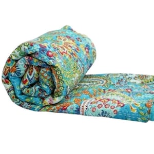 May include: A blue and green kantha quilt with a paisley pattern. The quilt is rolled up and has a white background.