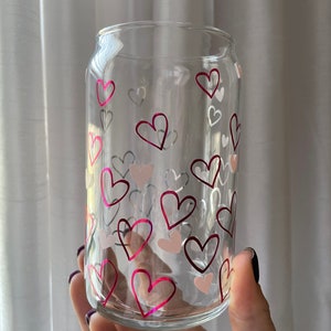 May include: A clear glass can with a pink and white heart pattern. The can is perfect for holding beverages.