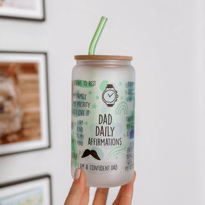 May include: A frosted glass tumbler with a bamboo lid and a green straw. The tumbler has a green, blue, and white design with the text "Dad Daily Affirmations" and "I am a confident dad".