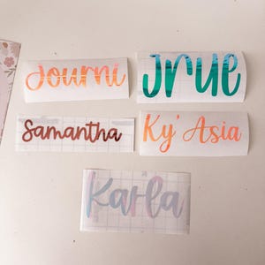 May include: Five custom vinyl name decals on transfer paper. The names include Journi in metallic copper, Jrue in metallic teal, Samantha in metallic bronze, Ky' Asia in metallic orange, and Karla in a multi-coloured pastel iridescent finish.