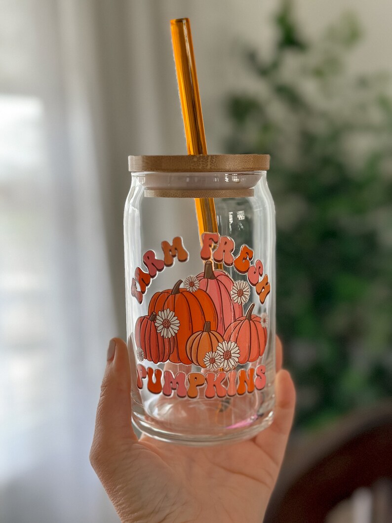 May include: A glass jar with a bamboo lid and a straw. The jar has a graphic of pumpkins with the text "Farm Fresh Pumpkins" in a retro font.