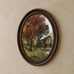 May include: An oval-shaped wall art piece featuring a landscape painting of a rustic timber-framed house nestled among trees with autumn foliage. The scene includes a small stream and chickens in the foreground, all enclosed in a dark brown frame.