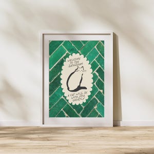 May include: A framed wall art print featuring a cream-colored scalloped oval containing a black line drawing of a cat and the text: Welcome to the bathroom, a cat will be with you shortly. The background is a pattern of dark green rectangular tiles.