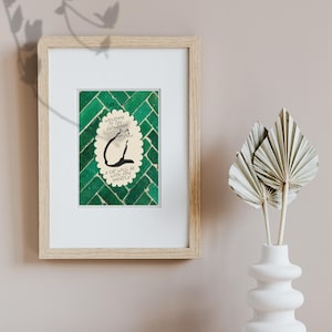 May include: A framed print featuring a green tiled background and a central scalloped oval containing a black line drawing of a cat. The text reads: Welcome to the bathroom, a cat will be with you shortly. The frame is light wood with a white mat.