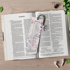 May include: An open Bible with a floral bookmark that says "January" and a black tassel. The Bible is open to the book of Genesis.