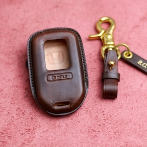 May include: A brown leather key fob with a gold metal clasp and a small leather tag that says "R.G.".