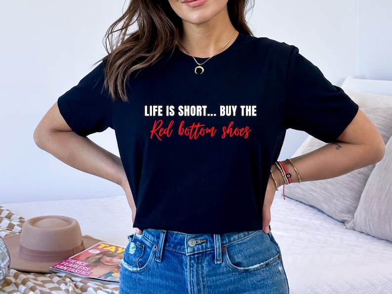 Pu&ograve; includere: Una maglietta nera con la scritta "Life is short... buy the red bottom shoes" in lettere bianche e rosse.
