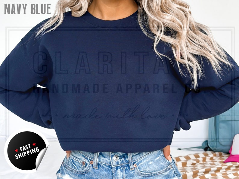 Model is wearing a blank navy blue crew neck sweatshirt.  The sweatshirt is made of a soft, comfortable fabric and has a relaxed fit. The sweatshirt is perfect for everyday wear or for special occasions.