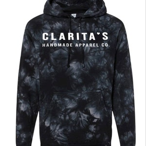 Puede incluir: Sudadera con capucha de color negro tie-dye con texto blanco que dice "Clarita's Handmade Apparel Co."