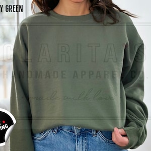 Model is wearing a blank military green crew neck sweatshirt.  The sweatshirt is made of a soft, comfortable fabric and has a relaxed fit. The sweatshirt is perfect for everyday wear or for special occasions.