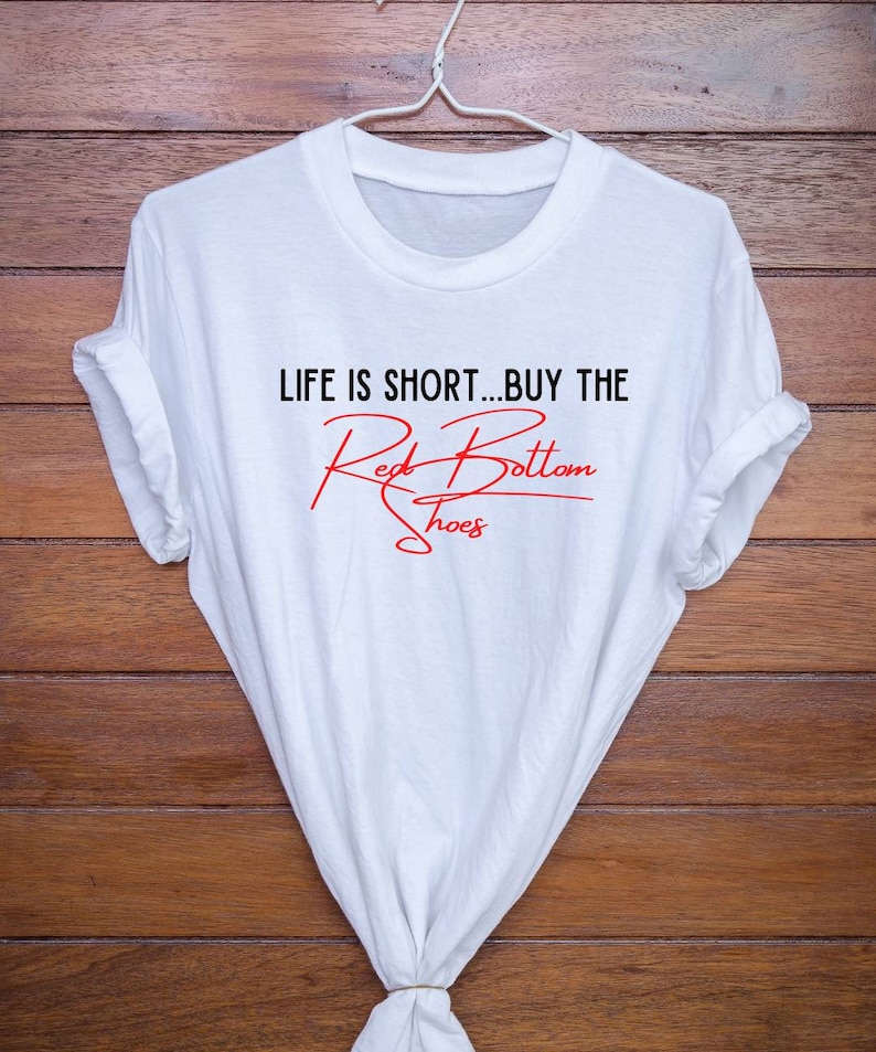 K&ouml;nnte beinhalten: Wei&szlig;es T-Shirt mit dem Text "Life is short...buy the Red Bottom Shoes" in schwarzer und roter Schrift.