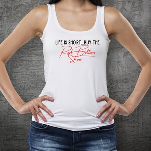 K&ouml;nnte beinhalten: Ein wei&szlig;es Tanktop mit dem Text "LIFE IS SHORT...BUY THE Red Bottom Shoes" in roten Buchstaben.