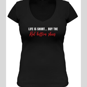 Pu&ograve; includere: Maglietta nera a collo a V con il testo "LIFE IS SHORT... BUY THE Red bottom shoes" in lettere bianche e rosse.