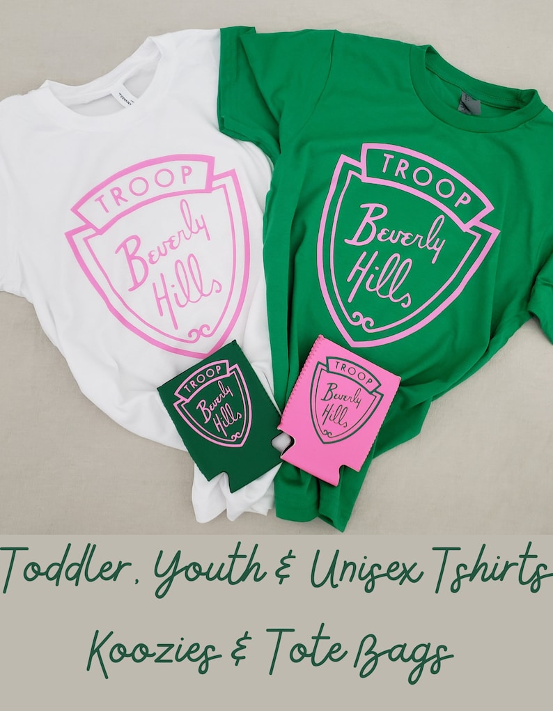 Puede incluir: Dos camisetas blancas y verdes con un dise&ntilde;o de escudo rosa que dice "TROOP Beverly Hills". Dos enfriadores de bebidas rosas y verdes a juego con el mismo dise&ntilde;o.