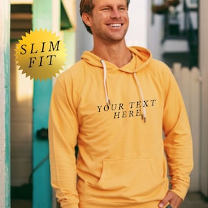 May include: A yellow slim fit hoodie with a white drawstring and the text "YOUR TEXT HERE" printed on the front.