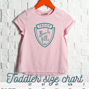 Puede incluir: Camiseta rosa para ni&ntilde;o peque&ntilde;o con un logotipo verde y blanco que dice "TROOP Beverly Hills". La camiseta tiene una tabla de tallas con medidas en pulgadas para las tallas 2T, 3T, 4T, 5/6 y 7.