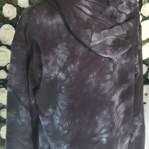 Puede incluir: Una sudadera con capucha negra tie-dye con capucha con cord&oacute;n. La sudadera tiene un corte holgado y una sensaci&oacute;n suave y c&oacute;moda.
