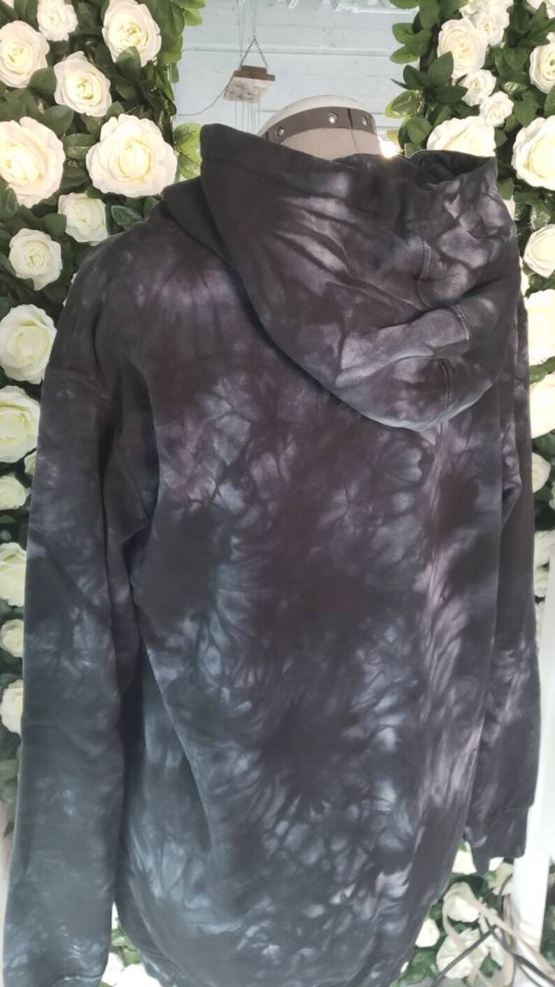 Puede incluir: Una sudadera con capucha negra tie-dye con capucha con cord&oacute;n. La sudadera tiene un corte holgado y una sensaci&oacute;n suave y c&oacute;moda.