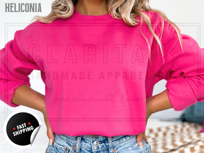 Model is wearing a blank hot pink crew neck sweatshirt.  The sweatshirt is made of a soft, comfortable fabric and has a relaxed fit. The sweatshirt is perfect for everyday wear or for special occasions.