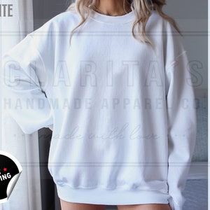 Model is wearing a blank white crew neck sweatshirt.  The sweatshirt is made of a soft, comfortable fabric and has a relaxed fit. The sweatshirt is perfect for everyday wear or for special occasions.
