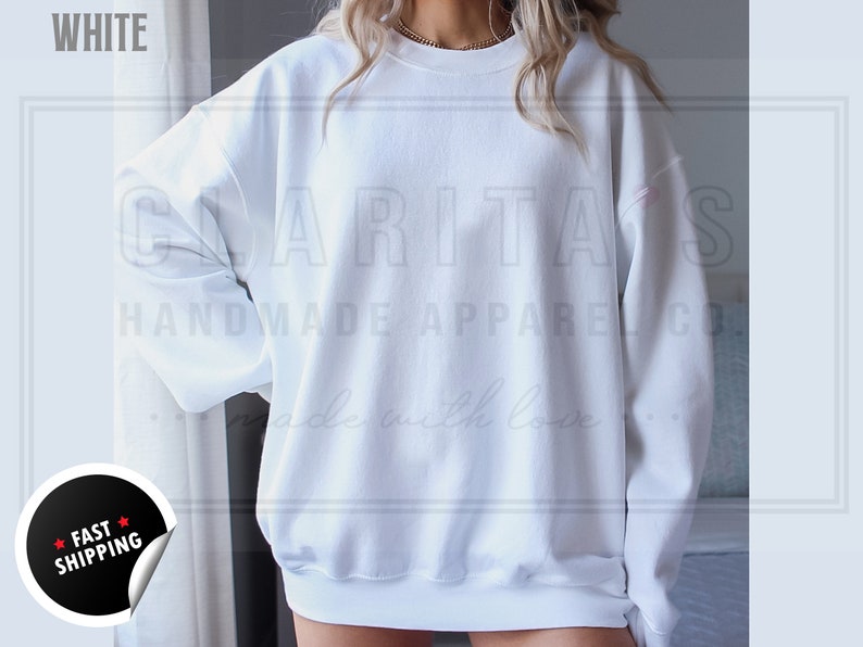 Model is wearing a blank white crew neck sweatshirt.  The sweatshirt is made of a soft, comfortable fabric and has a relaxed fit. The sweatshirt is perfect for everyday wear or for special occasions.