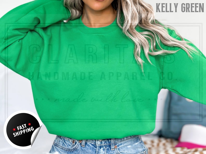 Model is wearing a blank Kelly green crew neck sweatshirt.  The sweatshirt is made of a soft, comfortable fabric and has a relaxed fit. The sweatshirt is perfect for everyday wear or for special occasions.