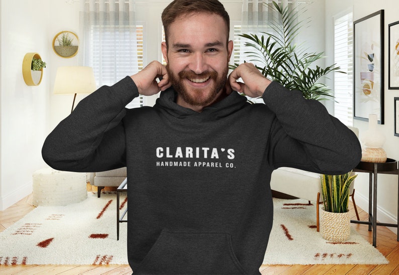 May include: A dark gray hooded sweatshirt with the text "CLARITA'S HANDMADE APPAREL CO." in white.