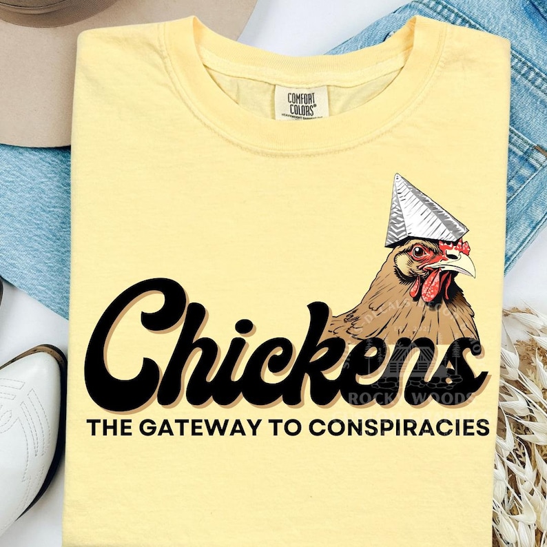 May include: A yellow t-shirt with a black graphic of a chicken wearing a tinfoil hat. The text "Chickens The Gateway to Conspiracies" is printed below the chicken.