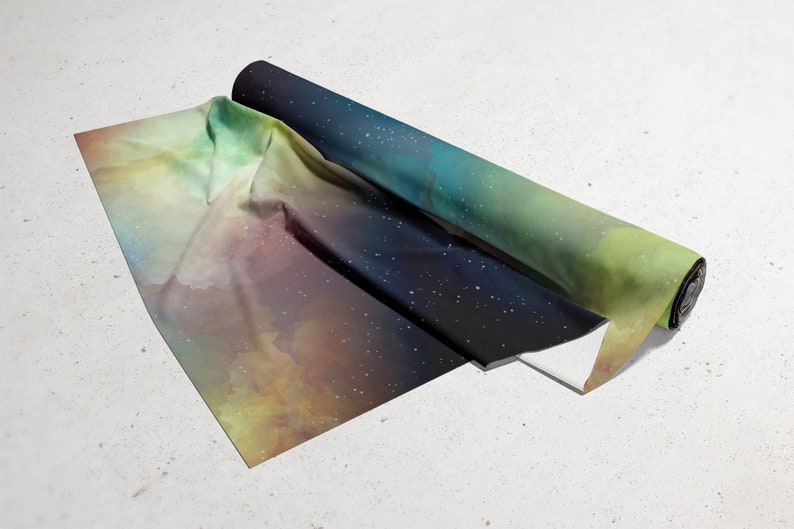 Puede incluir: Un rollo de tela con estampado de galaxia que presenta un fondo azul oscuro con estrellas blancas y un degradado de verde, amarillo y naranja.