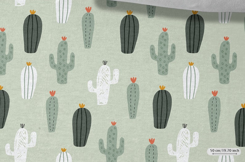 May include: A green fabric with a repeating pattern of white, green, and black cactus illustrations. The fabric is 50 cm (19.70 inches) wide.