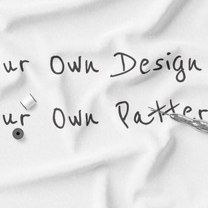 以下が含まれることがあります： 白い布に黒いマーカーで「Your Own Design」と「Your Own Pattern」と書かれています。布の上に白い糸の糸巻きが2つと銀色の裁縫ばさみがあります。