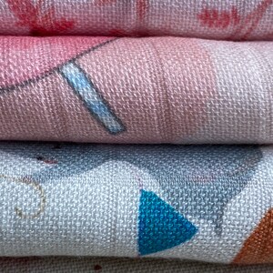 K&ouml;nnte beinhalten: Ein Stapel aus drei weichen, gewebten Babydecken. Die obere Decke ist rosa mit einem wei&szlig;en und blauen Design. Die mittlere Decke ist wei&szlig; mit einem grauen, blauen und orangefarbenen Design. Die untere Decke ist wei&szlig; mit einem goldenen Design.