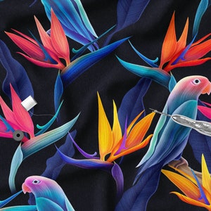 May include: A dark blue fabric with a repeating pattern of colourful bird of paradise flowers and blue parrots. The fabric has a subtle texture and a slightly iridescent sheen.