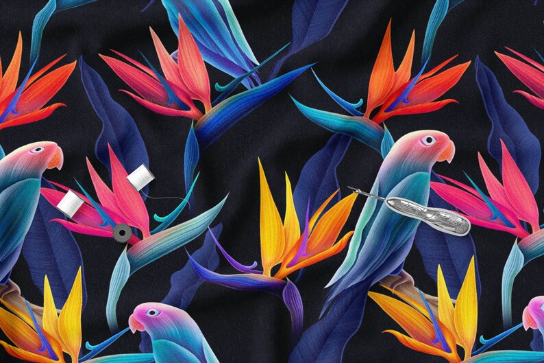 May include: A dark blue fabric with a repeating pattern of colourful bird of paradise flowers and blue parrots. The fabric has a subtle texture and a slightly iridescent sheen.