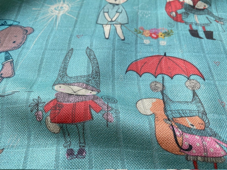 K&ouml;nnte beinhalten: Ein blauer und wei&szlig;er Stoff mit einem sich wiederholenden Muster von Tieren, die H&uuml;te tragen und Regenschirme halten. Zu den Tieren geh&ouml;ren ein B&auml;r, ein Kaninchen und ein Eichh&ouml;rnchen.