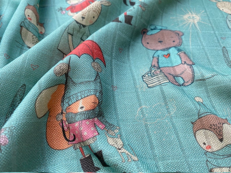 K&ouml;nnte beinhalten: Ein blauer Stoff mit einem sich wiederholenden Muster aus Comic-Tieren. Zu den Tieren geh&ouml;ren ein Fuchs mit blauem Hut und Schal, ein B&auml;r mit blauem Hemd, ein Eichh&ouml;rnchen mit rotem Hemd und eine Eule mit blauem Hemd. Der Stoff hat eine strukturierte Oberfl&auml;che.