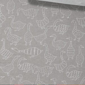 May include: A gray fabric with a white repeating pattern of geese. The geese are stylized and have different patterns on their bodies. The fabric is 50 cm (19.70 inches) wide.