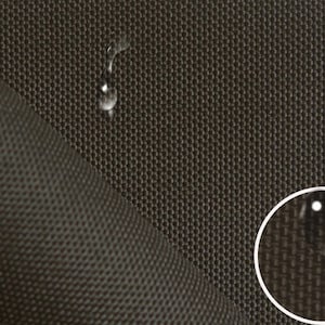 Puede incluir: Primer plano de una tela marrón oscura con un tejido texturizado. Las gotas de agua se posan sobre la superficie, demostrando las propiedades repelentes al agua de la tela.