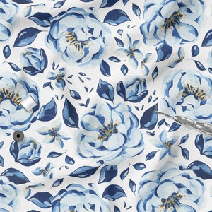 K&ouml;nnte beinhalten: Wei&szlig;er Stoff mit einem sich wiederholenden Muster aus gro&szlig;en blauen Aquarellblumen, kleineren blauen Bl&uuml;ten und dunkelblauen Bl&auml;ttern. Zwei Spulen wei&szlig;en Fadens und ein silberner Nahttrenner sind sichtbar.